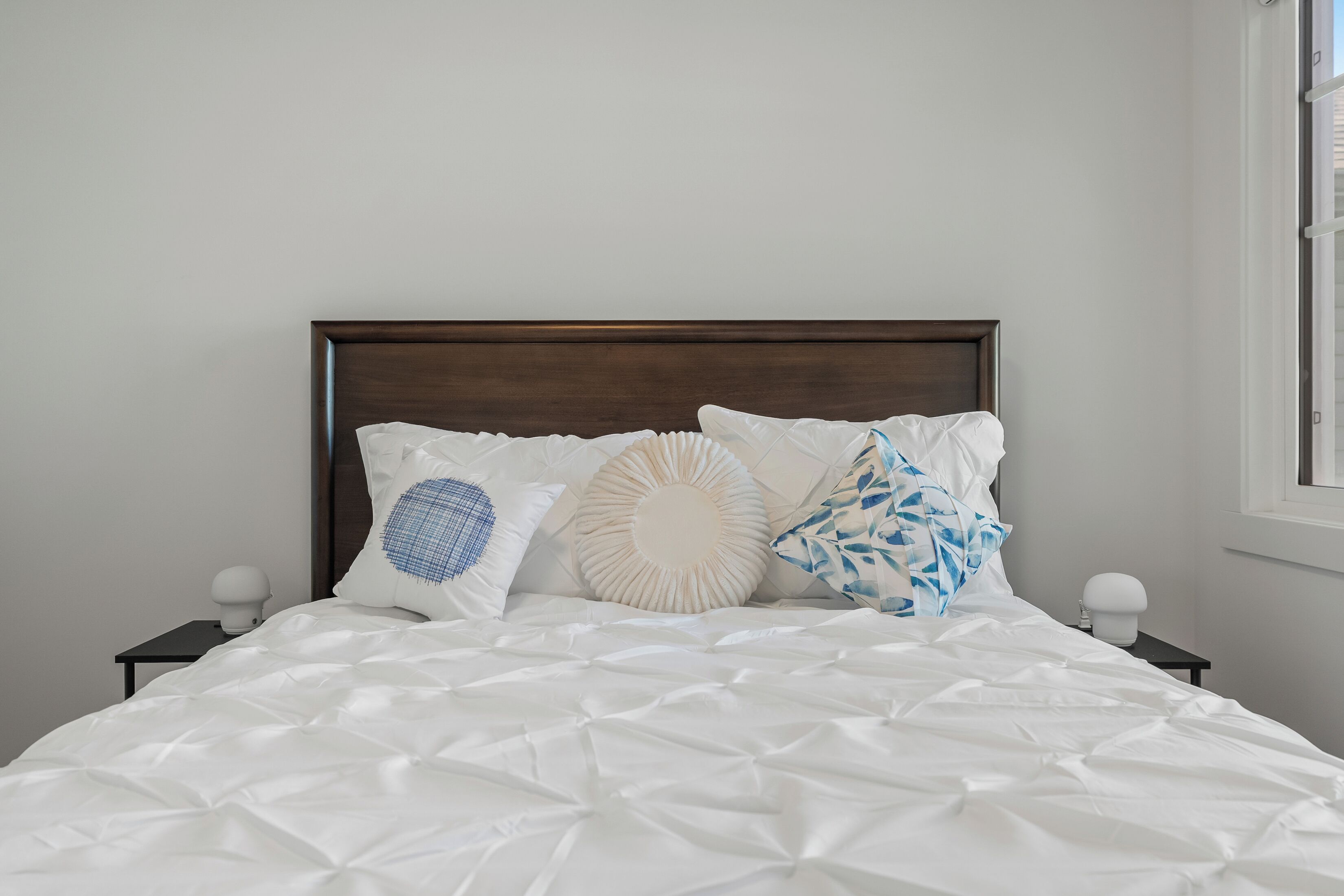 Un lit avec une couette blanche et quatre coussins décoratifs.