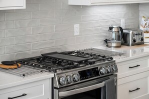 Eine moderne Küche mit einem Edelstahlherd, einer digitalen Bedienoberfläche für den Backofen und einer Kaffeemaschine.