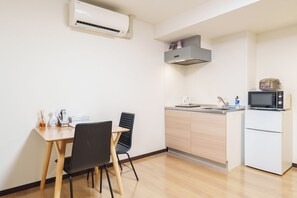A compact kitchen with a dining table, chairs, a microwave, and a refrigerator. - SERENE Osaka | 2 Minutes from Nipponbashi Station | 6F-606 | 35 ㎡, 2BR (osaka)