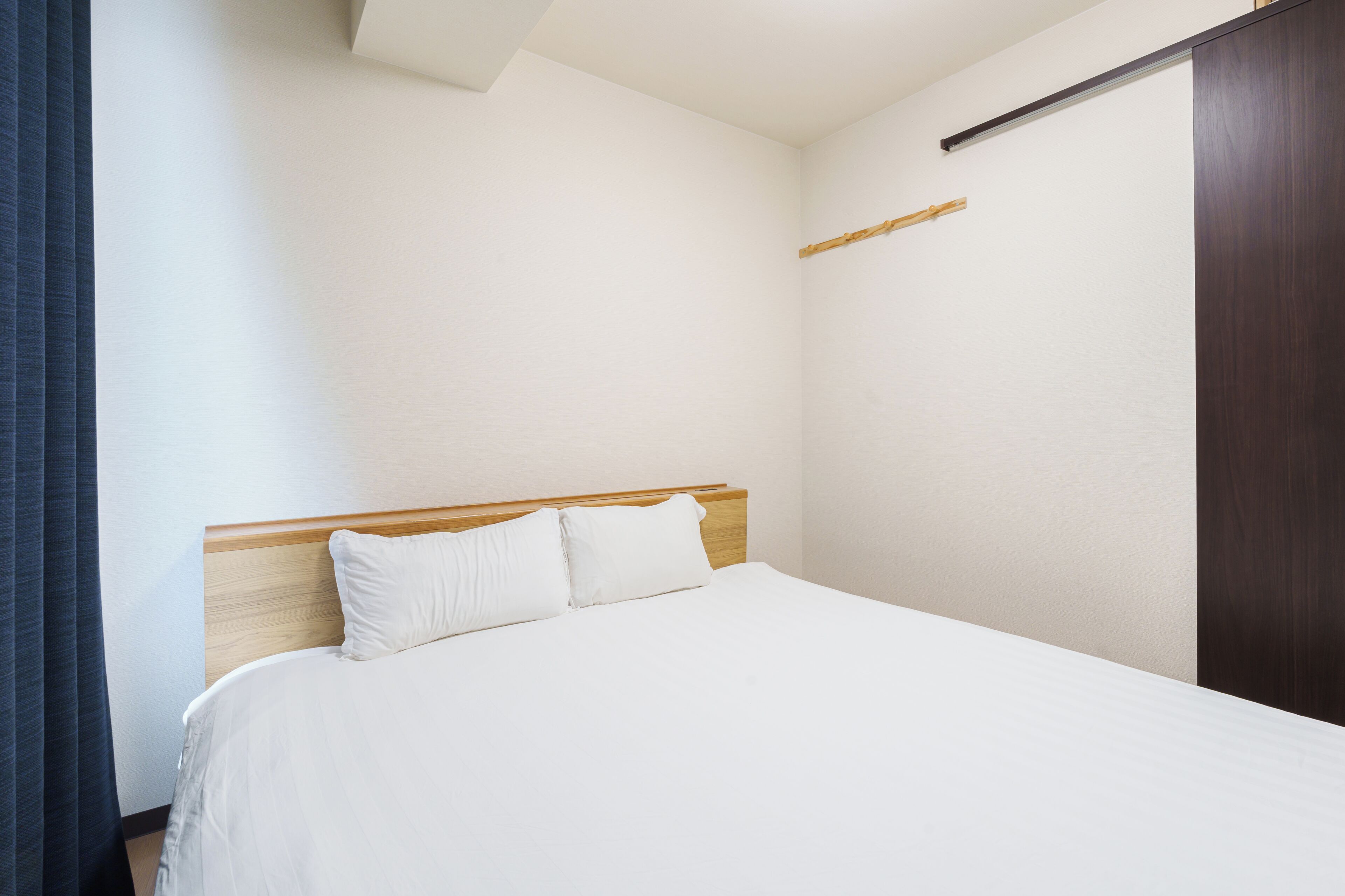 A bedroom with a bed, wooden headboard, and a wooden wardrobe.