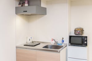 A compact kitchen with a built-in microwave, a kettle, and a sink. - SERENE Osaka | 2 Minutes from Nipponbashi Station | 6F-606 | 35 ㎡, 2BR (osaka)