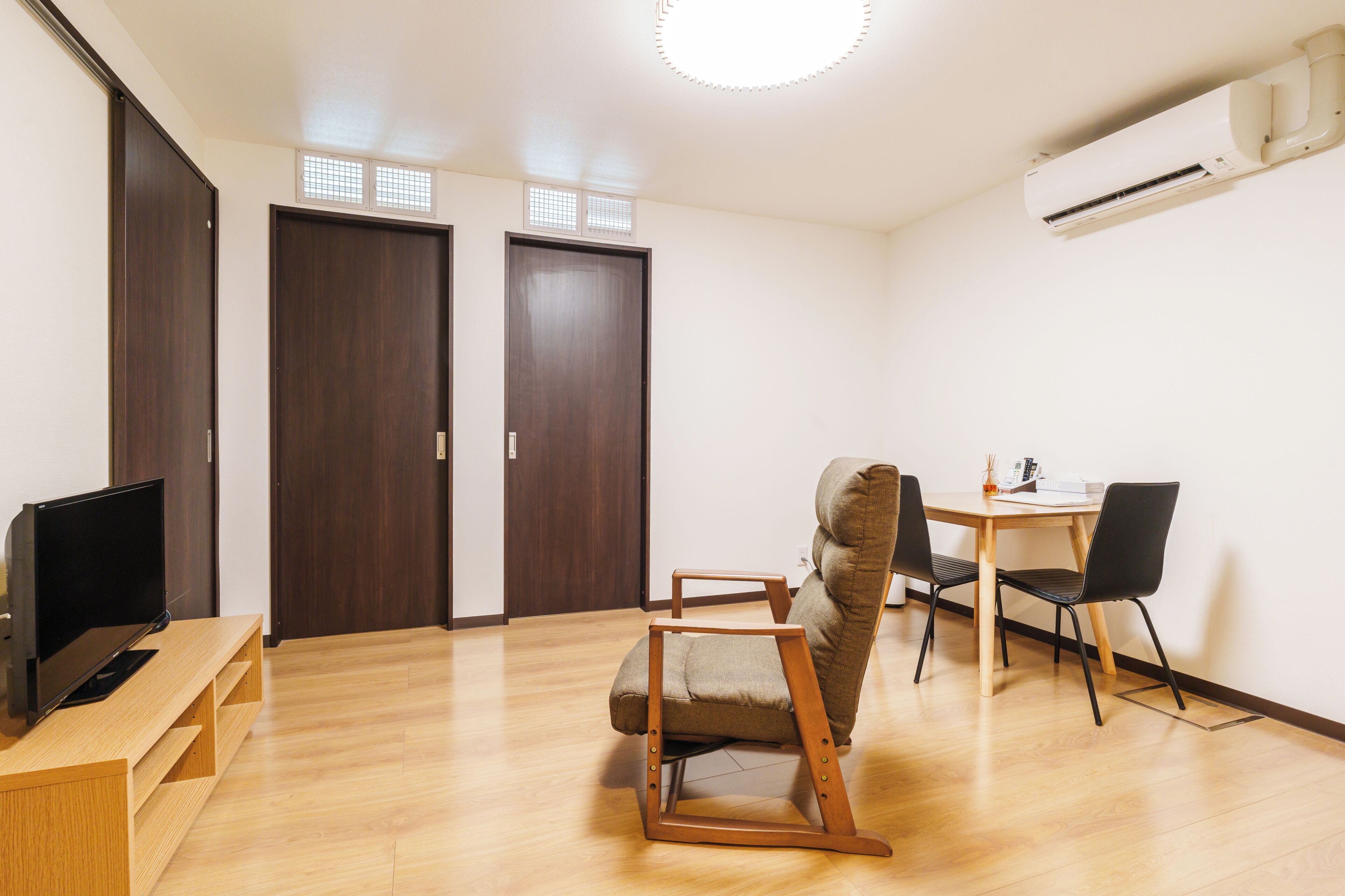 A room with a TV, a desk, two chairs, and a sofa.