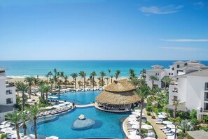 A resort with a central pool, palm trees, and a beach view. - Cabo Azul Resort - 2-bedroom/2-bath (San Jose Del Cabo)