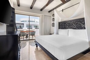 A hotel room with a large bed, a television, a balcony with a table and chairs, and a view of a building. - Cabo Azul Resort - 2-bedroom/2-bath (San Jose Del Cabo)