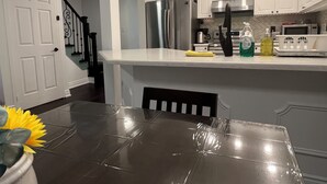 Et moderne køkken med hvide skabe, rustfrie hvidevarer og en marmor bordplade.