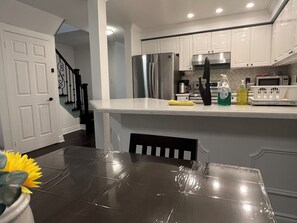 A modern kitchen with white cabinetry, stainless steel appliances, and a marble countertop. - Ravine Villa 4bed 4 bath fully privet (Richmond Hill)