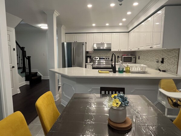A modern kitchen with white cabinets, stainless steel appliances, and a central island.