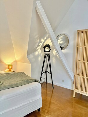 A bedroom with a bed, a lamp, a tripod with a clock, and a wooden cabinet. - Holiday apartment in heart of Møn (Stege)