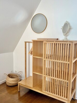 A wooden crib with a slatted design, a small round mirror, and a woven basket on the floor.