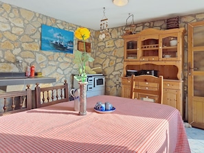 Ein Zimmer mit einer Steinwand, einem Gemälde, einem Holzschrank und einem Tisch mit kariertem Tuch.