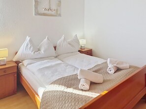 Uma cama bem arrumada com almofadas e um cobertor, um abajur e uma obra de arte na parede.