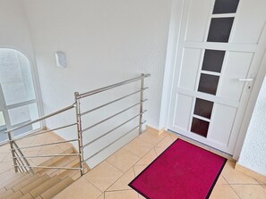 Un escalier avec des rampes en métal menant à une porte dotée d’un panneau de verre.