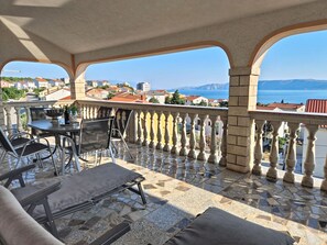 A terrace with a table and chairs, a view of the sea, and a stone floor. - Apartment Stina by Interhome (Novi Vinodolski)