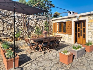 An outdoor patio with a stone floor, wooden furniture, and potted plants. - Apartment Loza by Interhome (Novi Vinodolski)