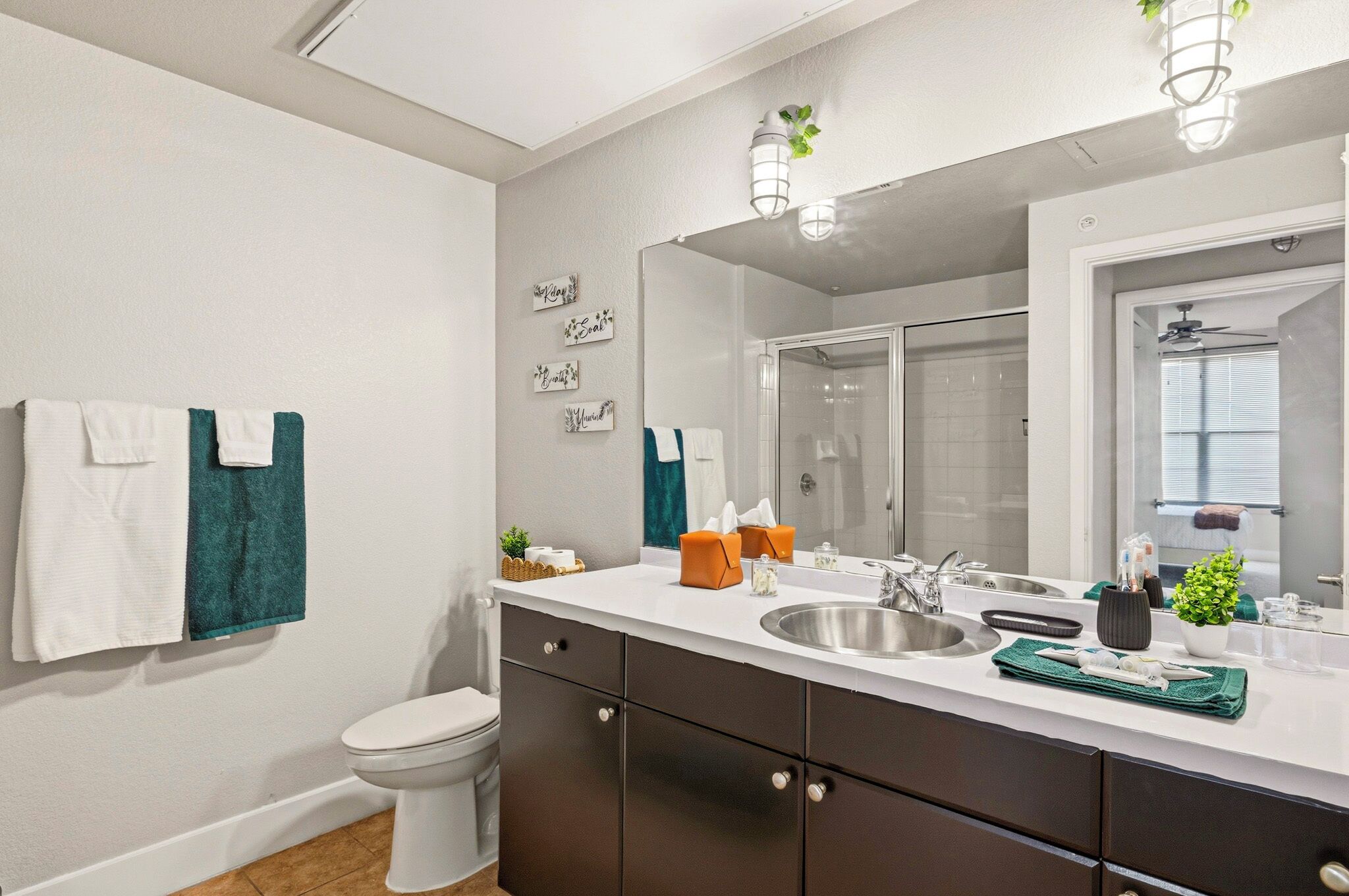 Une salle de bain moderne équipée de toilettes, d’un lavabo et d’une douche. On y trouve des serviettes et des articles de toilette sur le comptoir.