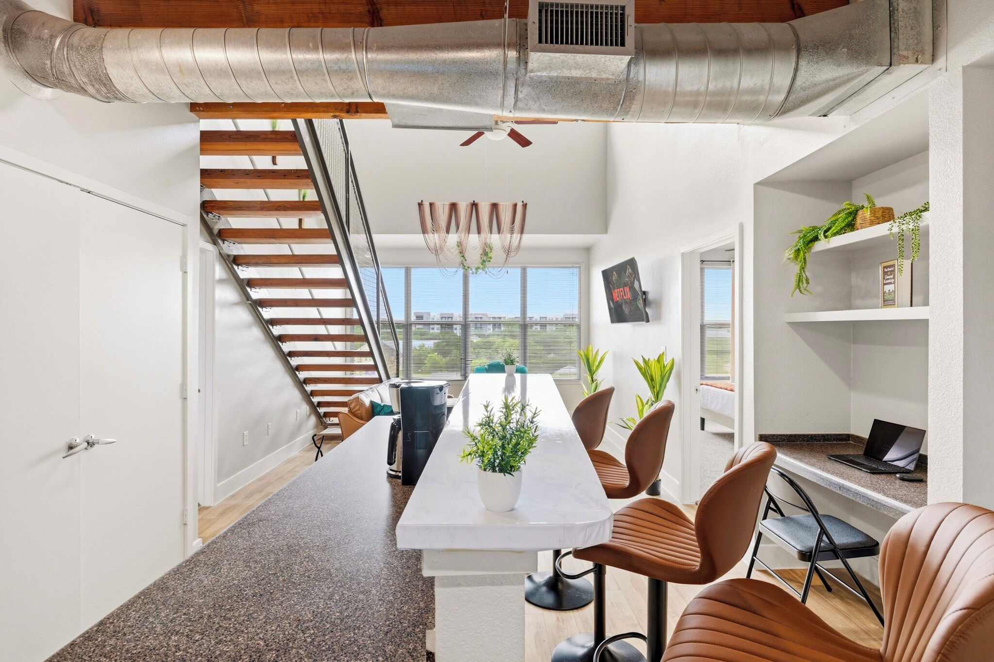 A modern interior with a staircase, a dining area, and a workspace.