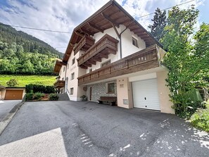 Ein zweistöckiges Gebäude mit einem geneigten Dach, hölzernen Balkonen und einer Garage.