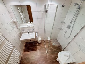 Une salle de bain moderne avec une douche à parois de verre, un lavabo blanc et un miroir.