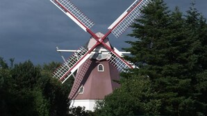 Eine Windmühle mit rotem und weißem Dekor, umgeben von Bäumen.