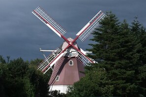 Eine Windmühle mit rotem und weißem Dekor, umgeben von Bäumen.