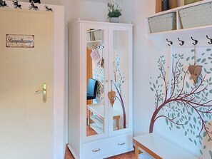 Ein Zimmer mit einem weißen Schrank, einem kleinen Tisch und einer Wand mit Baummotiv.