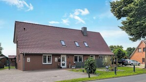 A two-story house with a sloped roof, a front porch, and a small garden area. - Das Dorfnest by Interhome (Wanna)
