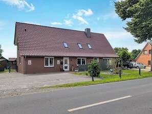Ein zweistöckiges Haus mit Satteldach, einer Veranda und einem kleinen Garten.
