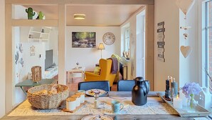 A cozy dining area with a wooden table set for a meal, a yellow armchair, and a clock on the wall. - Das Dorfnest by Interhome (Wanna)