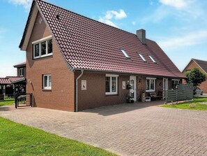 Ein zweistöckiges Ziegelhaus mit rotem Ziegeldach, einem gepflasterten Auffahrt und einem kleinen Garten.
