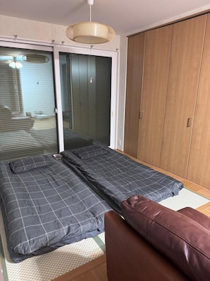 A bedroom with a bed, a brown leather chair, a wardrobe, and a sliding glass door.
