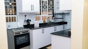 A kitchen with white cabinets, a black countertop, a stove, and a sink.