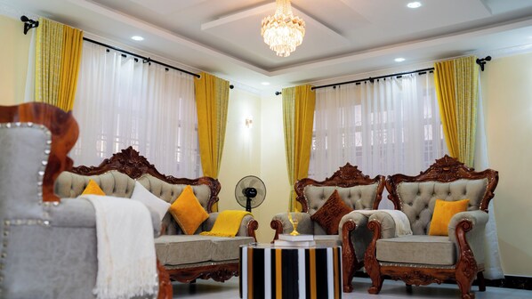 A room with two ornate sofas, a fan, and a chandelier.