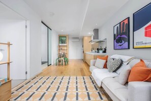 Una sala moderna con sofá, un tapete estampado y una cocina al fondo.