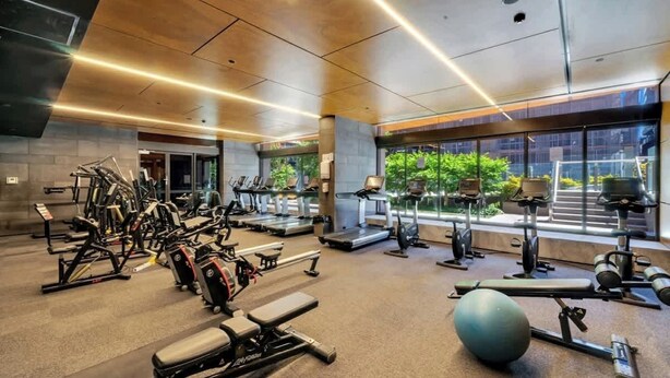 Ein modernes Fitnessstudio mit diversen Trainingsgeräten, großen Fenstern und Blick auf Grünflächen.