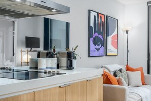 Una cocina moderna con estufa integrada, cafetera y televisor de pantalla plana.