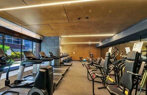 Un gimnasio con cintas de correr, elípticas y equipo de pesas.