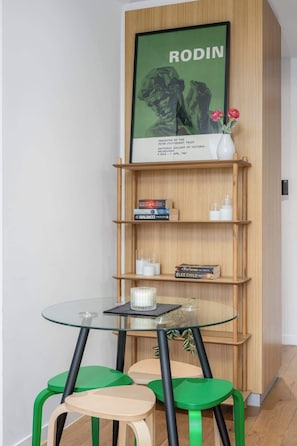 A room with a glass table, green chairs, a wooden bookshelf, and a framed picture. - LaneStay - 2BR Southern Cross & Marvel, Pool & Gym (Melbourne)