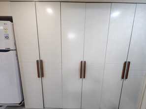 Una cocina con armarios blancos, tiradores de madera y un refrigerador blanco.