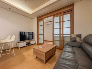 Ein modernes Wohnzimmer mit einer Couch, einem Fernseher, einem Couchtisch und einer Schiebetür.