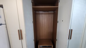 Ett rum med en garderob, en säng och ett litet träbord.