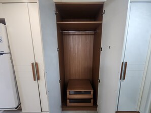 Ein Zimmer mit Kleiderschrank, Bett und kleinem Holztisch.