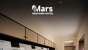 Una lavandería con varias lavadoras Haier, un cartel del Hotel Mars Respawn y suelo de madera.