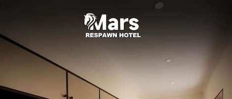 A laundry room with multiple Haier washing machines, a Mars Respawn Hotel sign, and a wooden floor.