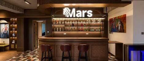 A bar area with a 'Mars' sign, bar stools, and a patterned floor.