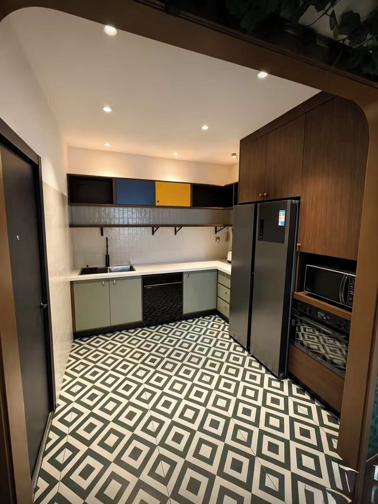 Uma cozinha compacta com piso estampado, eletrodomésticos embutidos e um nicho para micro-ondas.