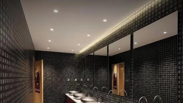 Une salle de bain moderne dotée d’un grand miroir, de plusieurs lavabos et d’un motif décoratif sur le mur.
