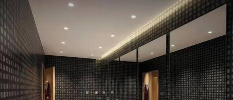 Un baño moderno con un espejo grande, varios lavamanos y un diseño de pared con motivos.