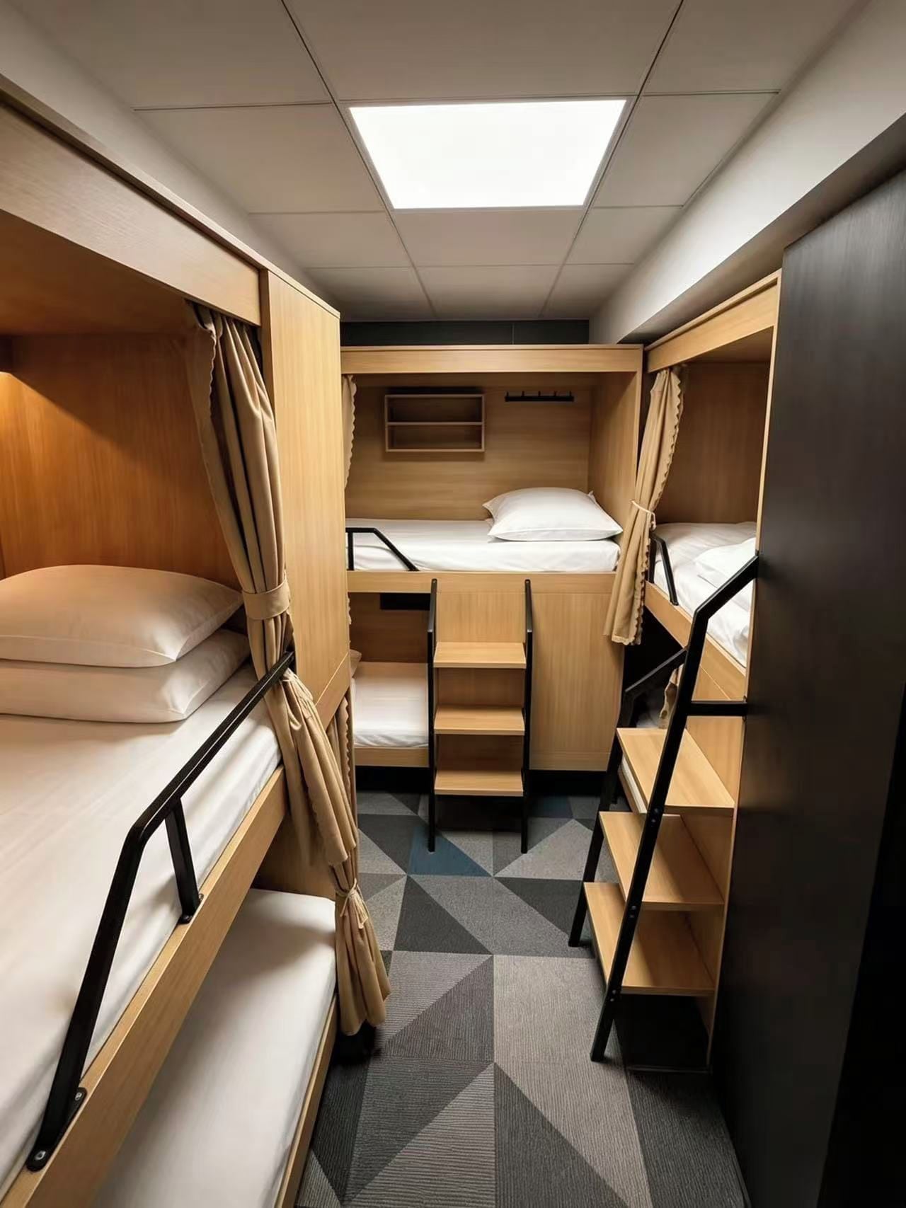 A compact, well-lit room with bunk beds, a small desk, and a staircase.
