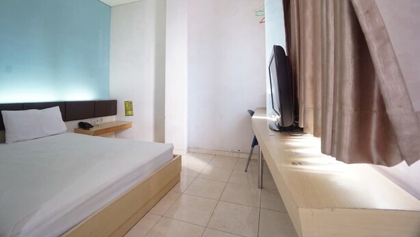 Une chambre d’hôtel avec un lit, un bureau, une télévision et un rideau.