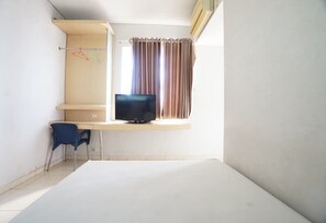 A room with a television on a stand, a desk, a chair, and a window with curtains.